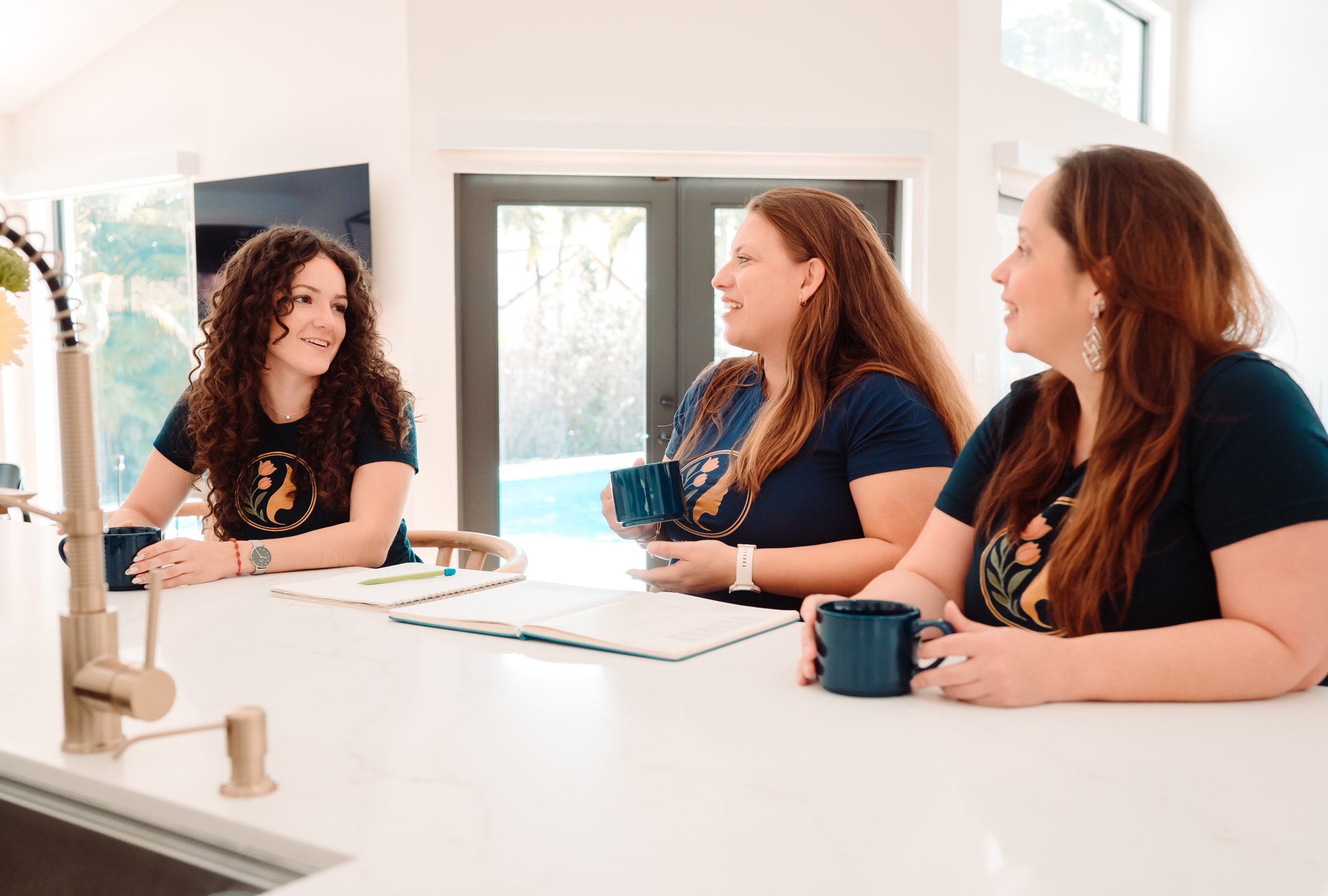 Three Empowered Woman team members talking at the office counter